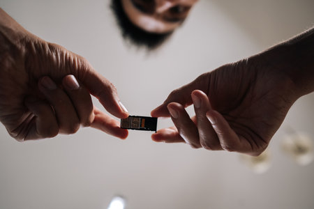 Low-angle view of man replacing sim card in mobile phone, providing efficient and reliable technical support to customer. Concept of smartphone maintenance and service.の写真素材