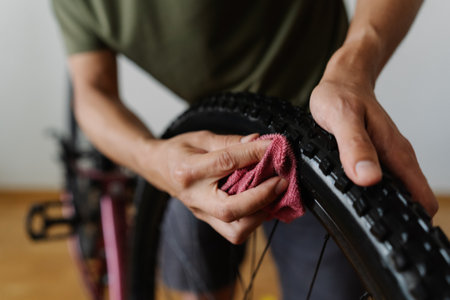 Bike owner male cleaning dirty tire of bicycle with cloth, focusing on detail to maintain optimal performance and enhance overall cycling experience at home. Concept of bike maintenance and service.の写真素材