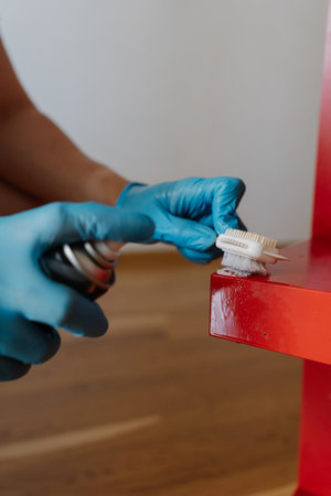 Vertical cropped shot of man wearing blue protective gloves removing adhesive stains, scrubbing red...