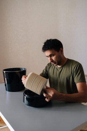 Vertical portrait of man cleaning filter of air humidifier, promoting clean and healthy air in living space while enhancing overall comfort and wellbeing. Concept of maintenance home appliance.の写真素材