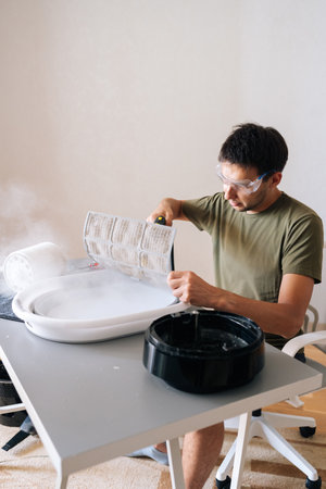Vertical portrait of technician in protective glasses cleaning air humidifier with steam cleaner, ensuring optimal performance and hygiene, removing dust, dirt, bacteria for indoor air qualityの写真素材