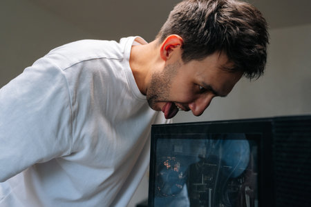 Cheerful computer technician male with a funny and frustrated expression, highlighting challenges of computer maintenance and repair. Concept of desktop PC service.の写真素材