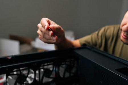 Close-up hands of unrecognizable computer technician assembling components within desktop pc case, focusing on maintenance and upgrades for enhanced hardware performance and reliability.の写真素材