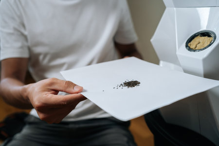 Close-up of agricultural technician holding paper with seeds, preparing for planting in modern hydroponic system with rockwool and hydroponic tower in background. Concept of home gardening.の写真素材
