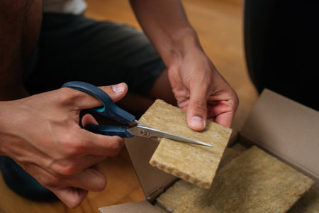 Close-up hands of unrecognizable gardener cutting piece of rockwool with scissors, preparing it for seed starting in hydroponic system. Concept of healthy and sustainable cultivation.の写真素材