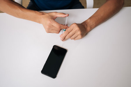 Top view of skilled repairman using syringe needle to repair broken smartphone in professional...