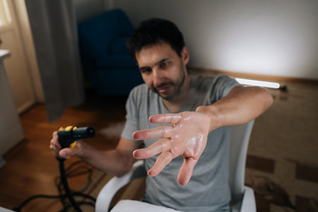 Man finding humor in everyday household chores, fooling around with steam cleaner holding out his wet, sweaty hand in playful gesture, adding lightheartedness to cleaning routine.の写真素材