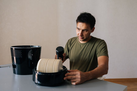 Focused cleaning service employee maintaining air humidifier filter, ensuring clean indoor air quality and optimal respiratory health in home environment. Concept of maintenance home appliance.の写真素材