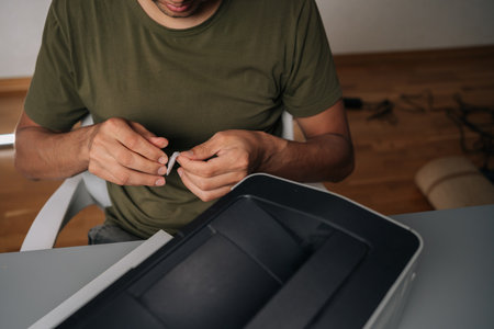 Top view of technician male cleaning printer with cloth, performing routine maintenance on essential...