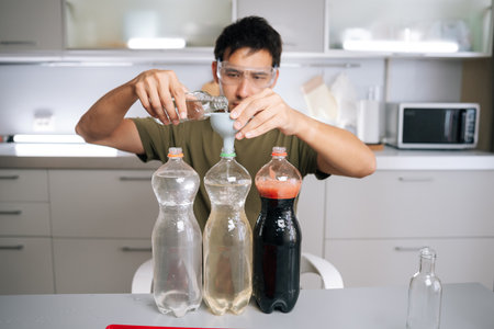 Agricultural technician wearing protective eyewear pouring chemical liquid through funnel into...