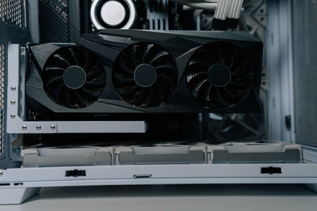 High-performance gpu with triple cooling fans mounted inside white pc case, close-up of modern...