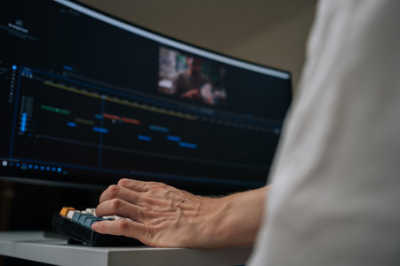 Editor working on professional video editing software, using computer workstation with wide monitor...