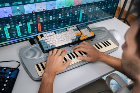 View from shoulder of audio engineer creating new music in professional studio setup, inputting...