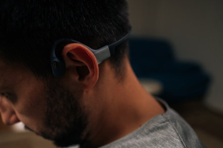 Close-up of man enjoying audio experience with bone conduction headphones, wirelessly transmitting...