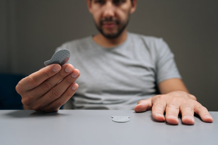 Man holding adhesive game thumb pad, ready to apply to smartphone screen for improved control and...