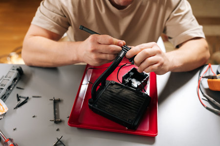 Close-up hand of young man performing computer cooling system maintenance, repairing all-in-one...