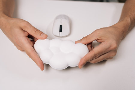 Person holding cloud-shaped wrist rest for computer mouse, providing ergonomic support and comfort...