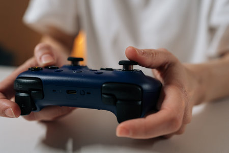 Person holding modern wireless video game controller, engaging in online gaming or e-sports,...
