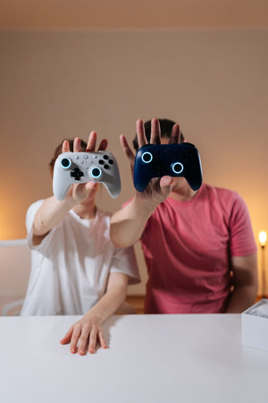 Vertical portrait of couple holding illuminated game controllers, showcasing latest technology for...