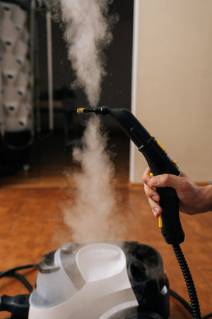 Vertical cropped shot of unrecognizable man using steam cleaning machine, releasing powerful hot vapor for effective sanitation and deep cleaning purposes, ensuring hygiene and freshness at home.の写真素材