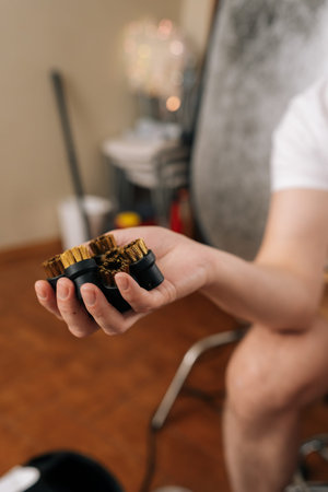 Vertical cropped shot of man holding collection of brass cleaning brushes, preparing for effective sanitization and deep scrubbing with steam cleaner appliance at home. Concept of household.の写真素材
