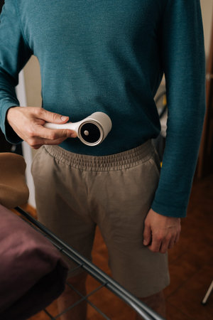 Person holding fabric shaver, cleaning lint from various garments, enhancing textile longevity, and performing essential laundry and clothing maintenance tasks.の写真素材
