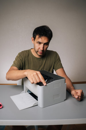 Vertical portrait of man cleaning laser printer with microfiber cloth, performing regular...