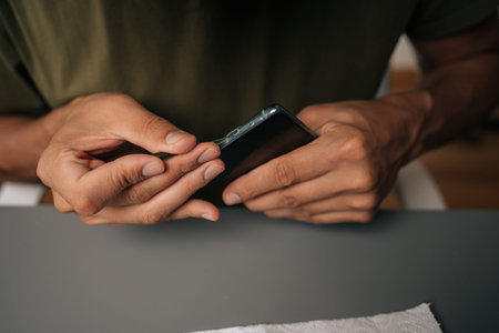 Close-up of unrecognizable technician cleaning smartphone using specialized tools sitting at table,...