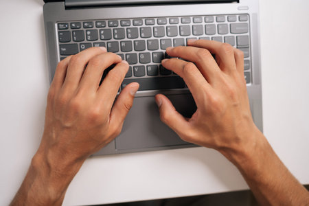 Top view of programmer male typing code on laptop keyboard, showcasing process of software...