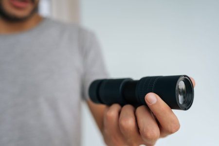 Close-up hands of unrecognizable person holding black monocular in hand, extending forward, focusing with optical instrument to observe something unseen. Concept of discovering, exploring, vision.