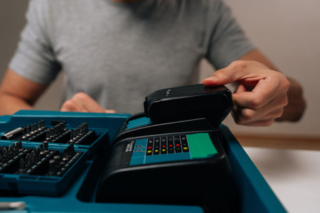Close-up cropped shot of worker preparing tools, charging power drill battery for upcoming diy project, demonstrating home improvement and maintenance skills with power equipment.