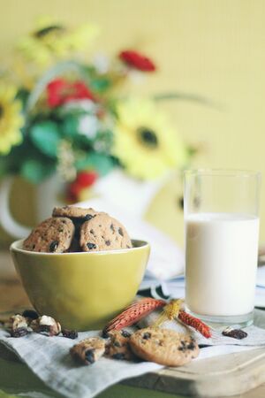 Domestic smell. Tasty cookies or biscuits with chocolate and milk on the napkin. Feel the home comfort with sweets. Delicious food and drinks concept, healthy eating for morning. Warm colors.の写真素材