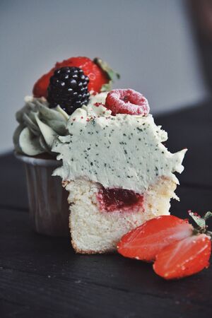 Strawberry creamy cupcakes with mint on black wooden kitchen background. Sweets for breakfest. Tasty food, beauty of delicious and art concept. Juicy colors, seasonal snack.の写真素材