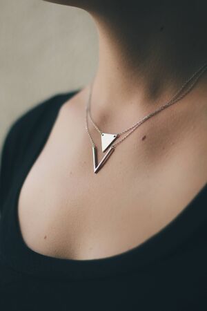 Tender jewelry on female neck, close up shot. Elegance accessories for look and beauty. Chain-let with pendant on neck, soft light. Gift for relationship. Fashion, love concept.の写真素材