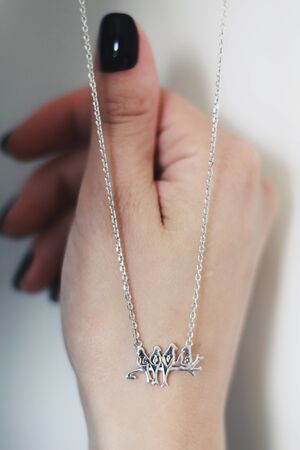 Tender jewelry for female neck, close up shot. Elegance accessories for look and beauty. Chain-let with pendant on hands, soft light. Gift for relationship. Fashion, love concept.の写真素材