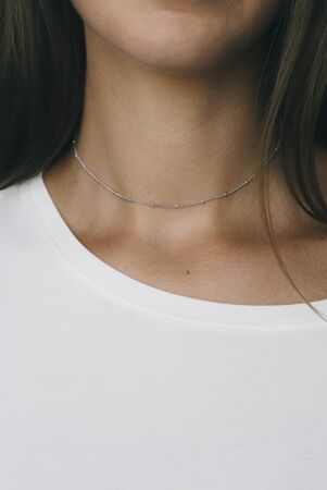 Tender jewelry on female neck, close up shot. Elegance accessories for look and beauty. Chain-let with pendant on neck, soft light. Gift for relationship. Fashion, love concept.の写真素材