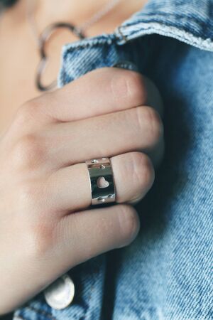 Tender jewelry on female hand, close up shot. Elegance accessories for look and beauty. Hand with rings on jeans, soft light. Gift for relationship. Fashion, love concept.の写真素材