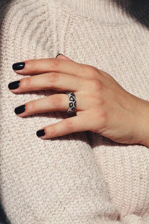Tender jewelry for female hands, close up shot. Elegance accessories for look and beauty. Rings on fingers in soft light with sweater. Gift for relationship. Fashion, love concept.の写真素材