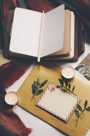 Opened book, green leaves, greeting postcard and candles. Autumn home comfort, warm. Evening...