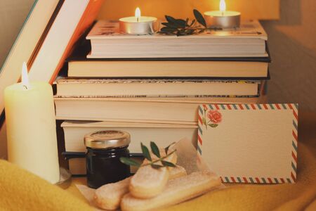 Books and candles, cakes, autumn home comfort and warm light. Evening or holidays atmosphere in family house. Time for reading. Chill, resting, education concept. Winter's cold days for domestic novel.の写真素材