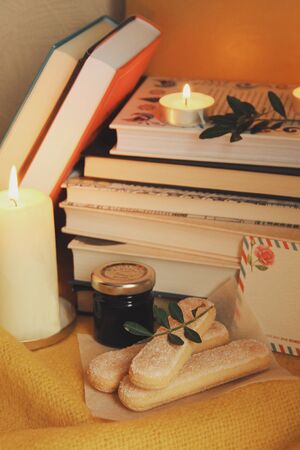Books and candles, cakes, autumn home comfort and warm light. Evening or holidays atmosphere in family house. Time for reading. Chill, resting, education concept. Winter's cold days for domestic novel.の写真素材