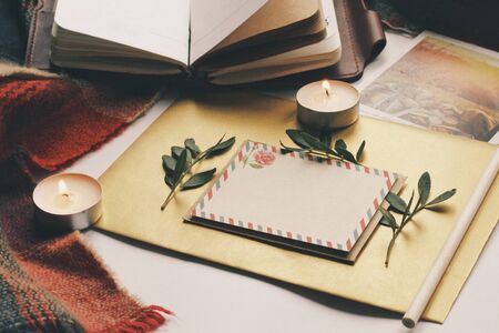 Opened book, green leaves, greeting postcard and candles. Autumn home comfort, warm. Evening atmosphere in family house. Time for greeting those who loves you. Holiday wishes, romantic. Flatlay.の写真素材