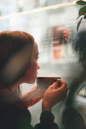 Caucasian young woman enjoying coffee drinking in cafe, close upの写真素材