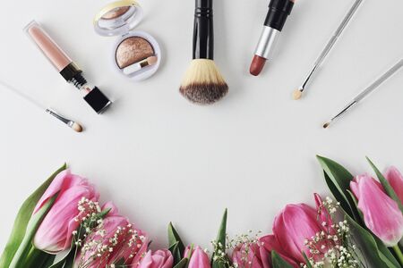 Tulips, beauty mood. Beautiful spring flowers bouquet with cosmetics for greetings on white background. Copyspace. Petals and leaves, make up compositionの写真素材