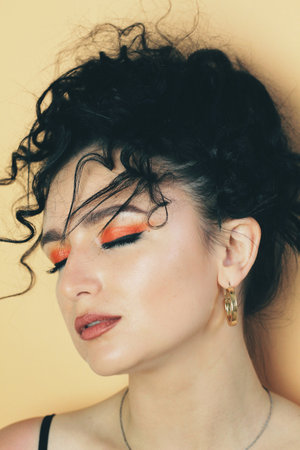 Smoky. Beautiful young brunette model with bright make-up and curly hairstyle. Fashion and beauty, using cosmetics. Vibrant colors of eyeshadow and lipstick. Saloon, make up artist, caucasian model.の写真素材