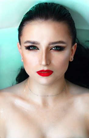 Beautiful young brunette model with bright make-up in bath, waterの写真素材