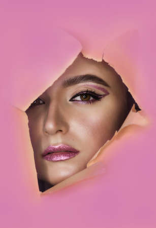 Beautiful young model with bright make-up in pink tropical backgroundの写真素材