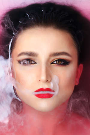 Beautiful young brunette model with bright make-up in bath, waterの写真素材