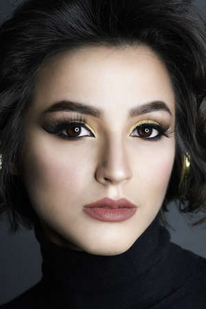 Beautiful young brunette model with bright make-up and curly hair. Fashion and beauty, using...