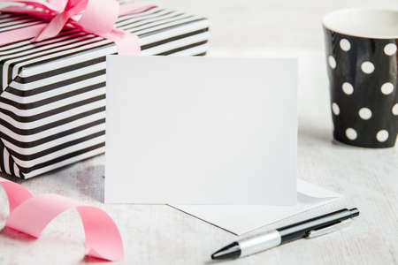 Empty greeting card. Wrapped gift and coffee cup in the background.の写真素材